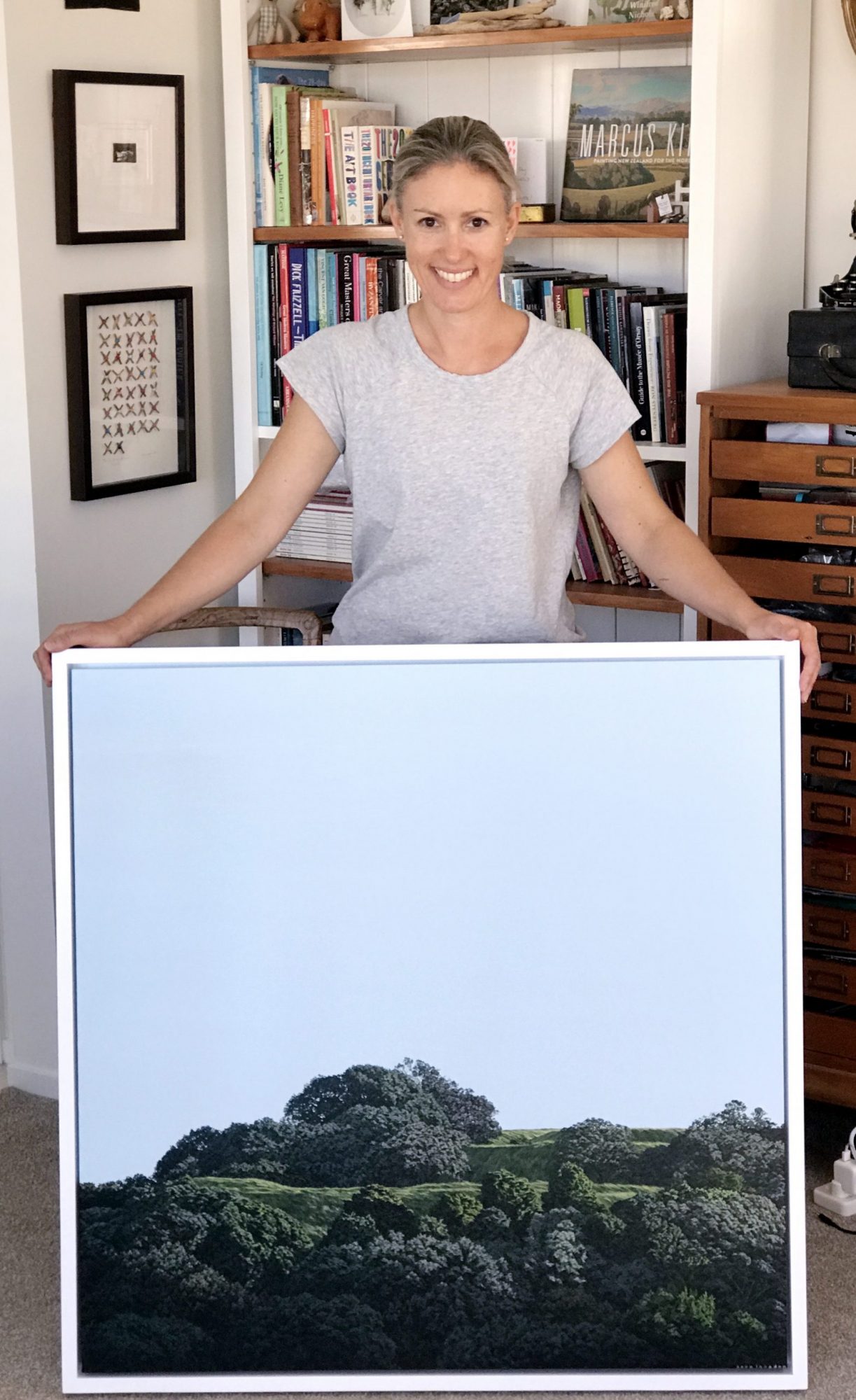 Picture of Sara holding an original painting of Mt Eden