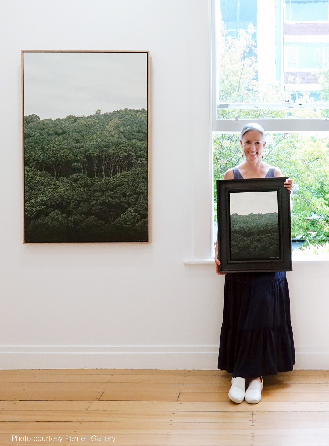 Picture of Sara holding an original painting of Mt Eden